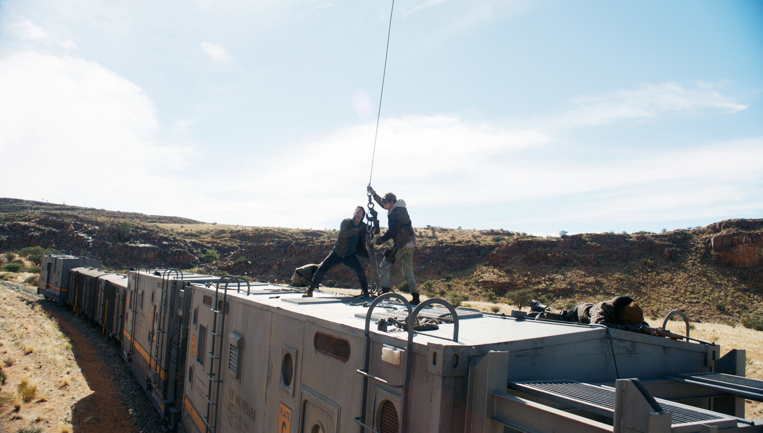 A behind the scenes photo of Dylan O&#x27;Brien being put in a harness for a stunt on top of a train