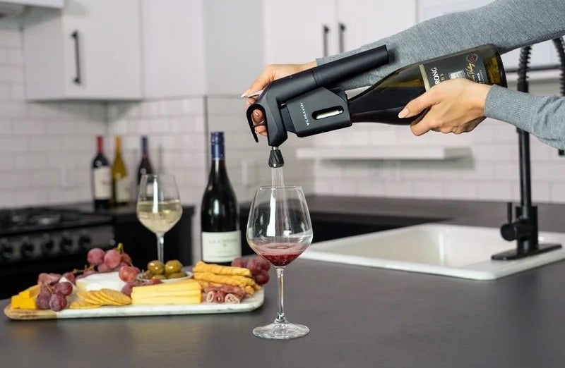 Model using wine device on a bottle of red wine.