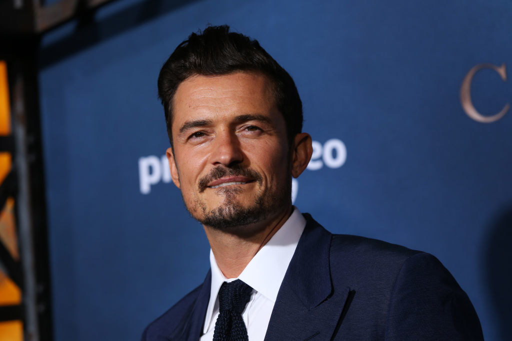 Orlando Bloom looks at something in the distance and smiles