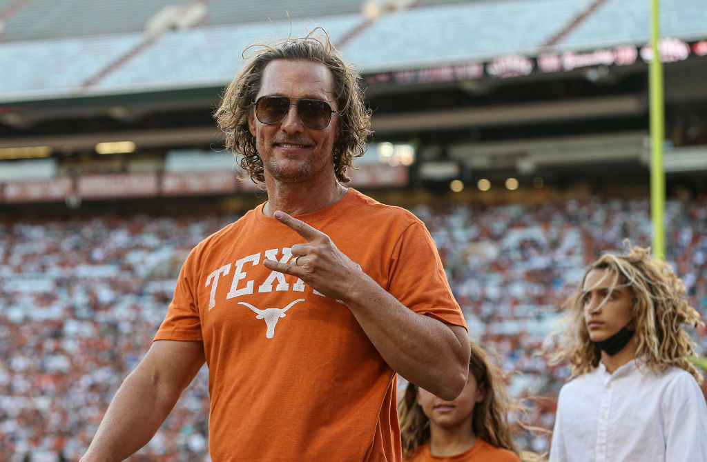 Matthew McConaughey gives the rock on symbol in a stadium