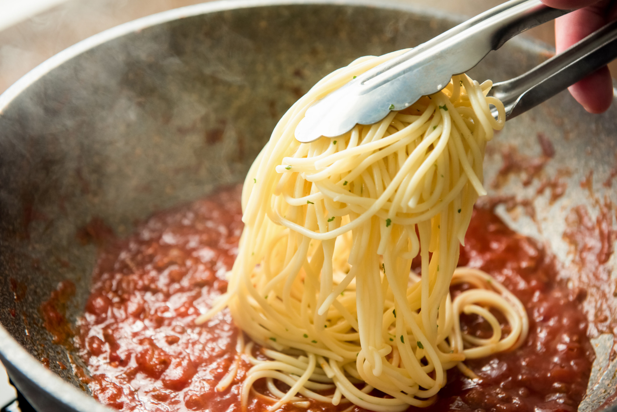 Putting spaghetti into Bolgonese sauce