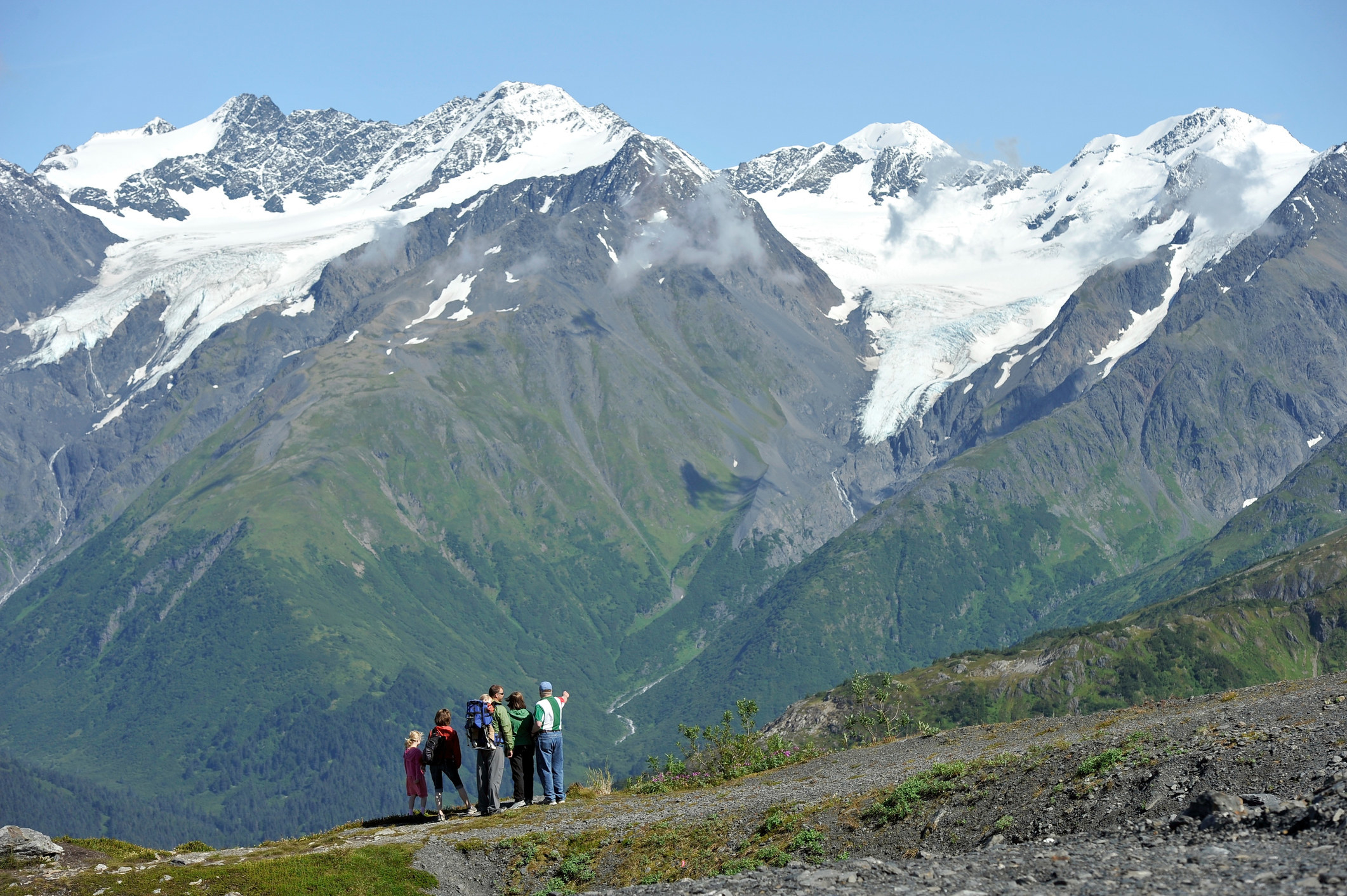 a group of hikers pointing to the top of a mountain