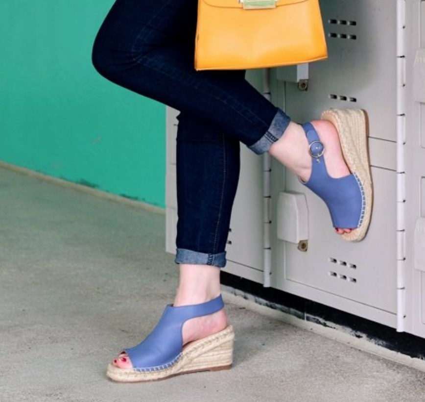 A model wearing a pair of blue peep toe wedges