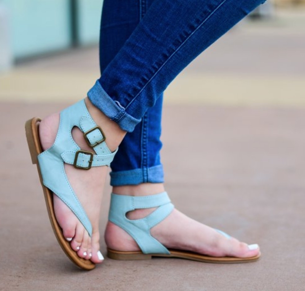 A model wearing blue faux leather wrap thong sandals