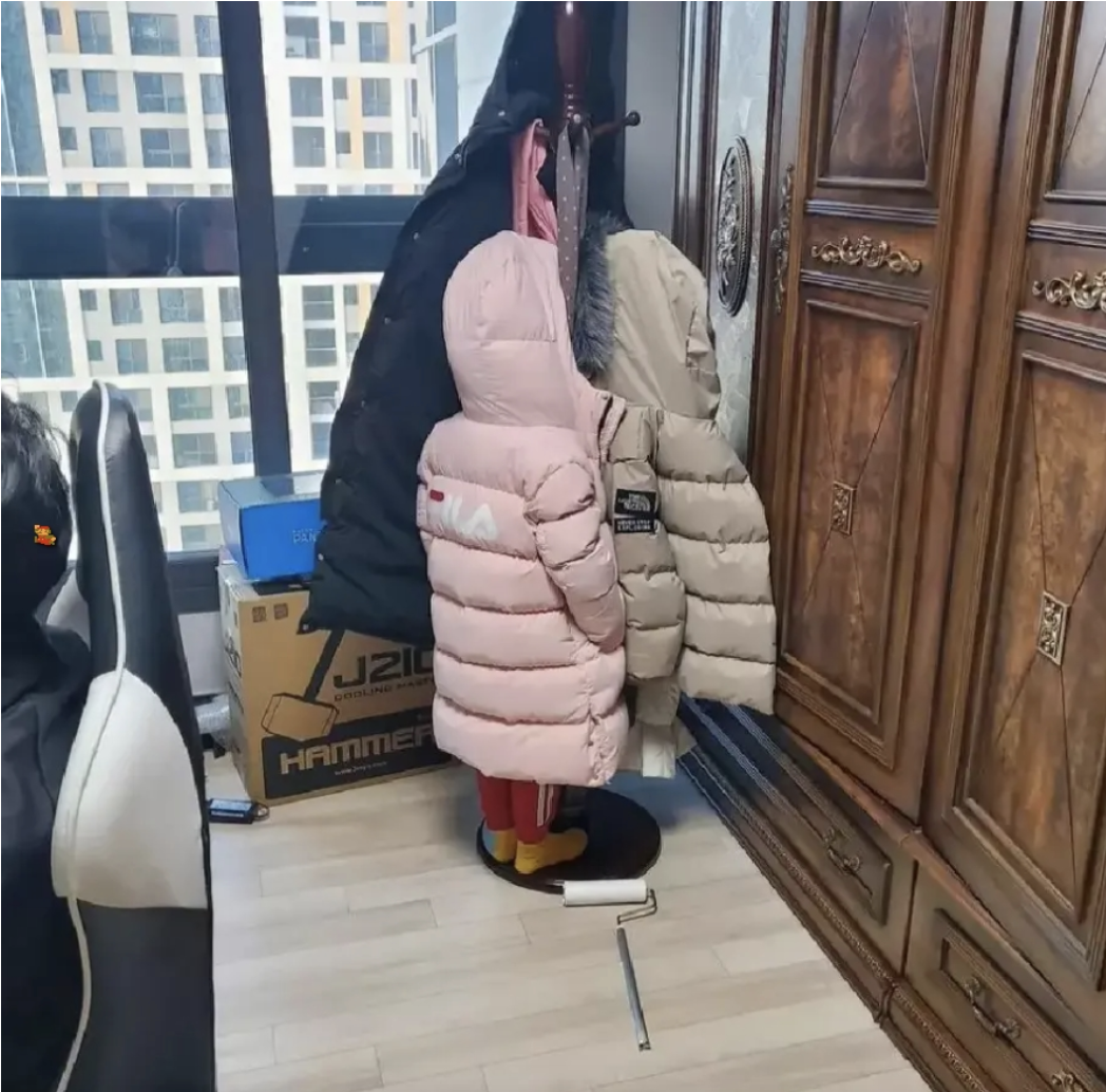 a kid hiding in the coat rack