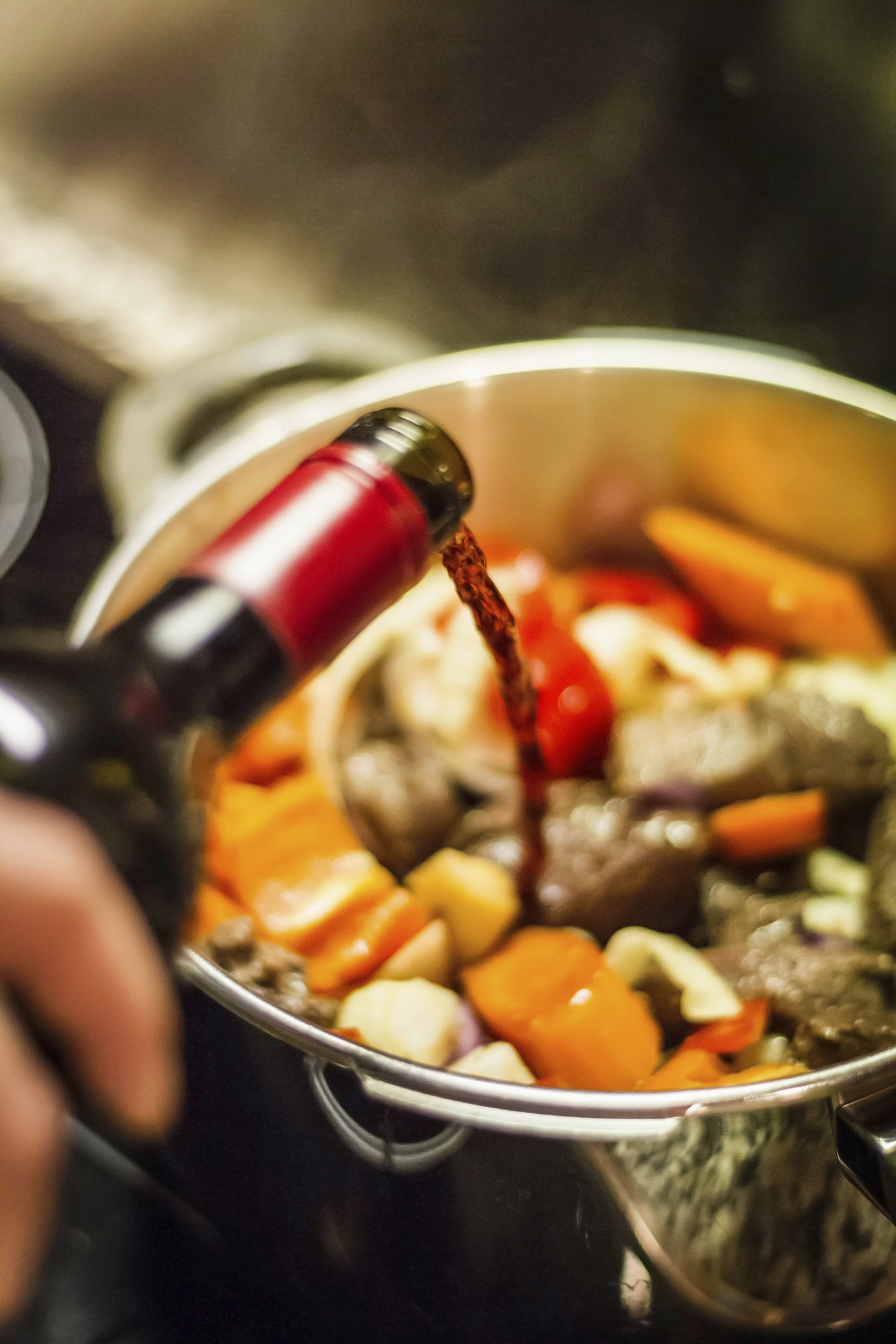 Wine being poured into a pot of vegetables