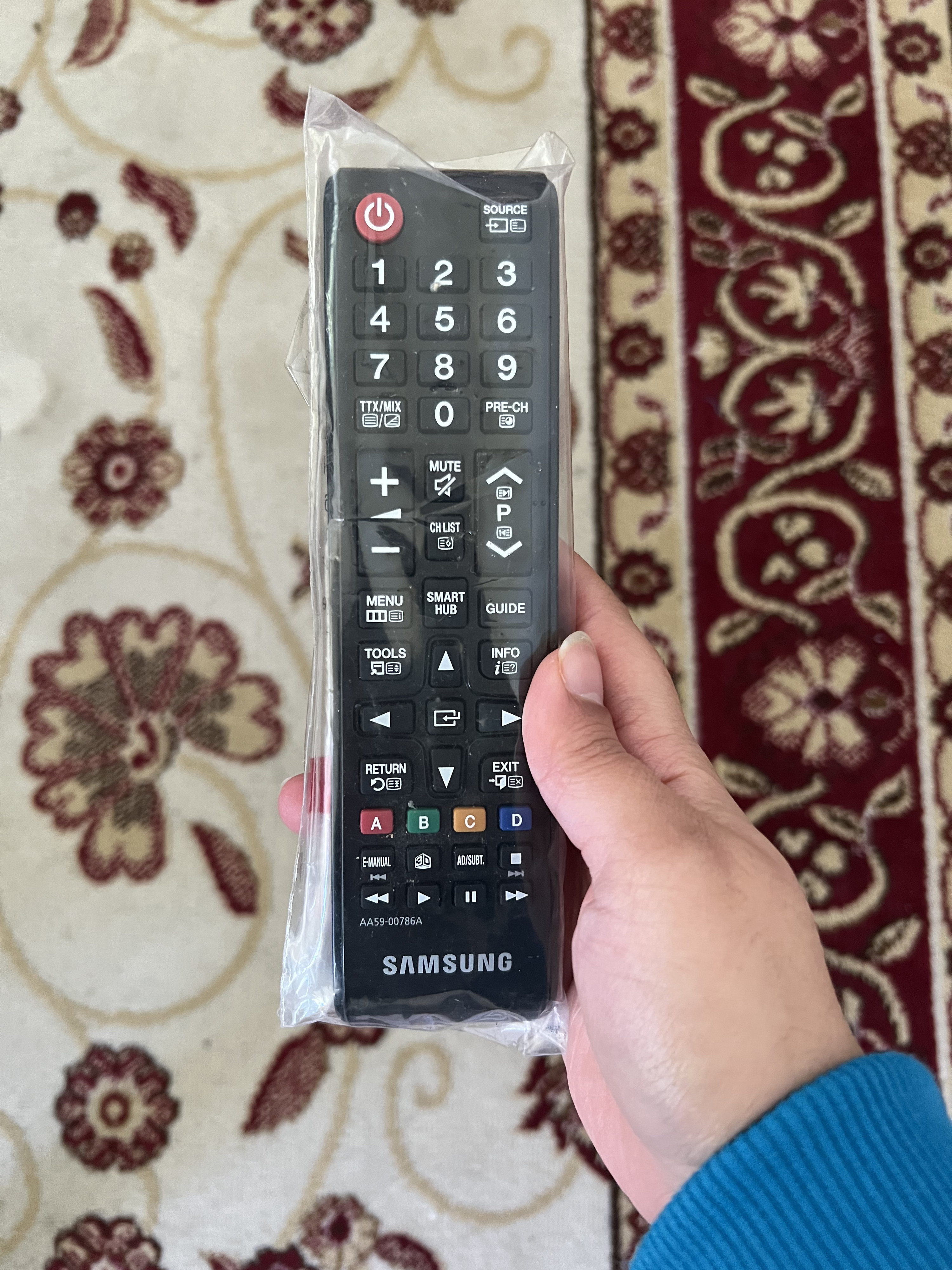 A handing holding a TV remote covered with plastic