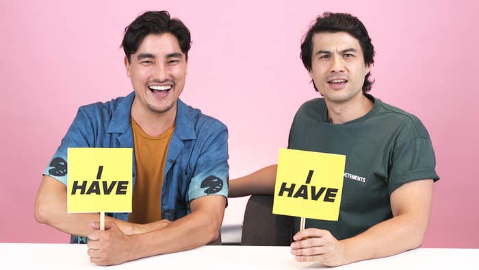 Remy Hii and Max Brown sitting down at a table and holding up signs that say &quot;I have&quot;