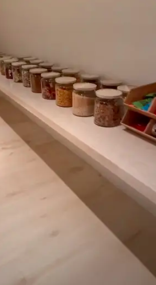 Inside Kim&#x27;s pantry, a single shelf holds rows of giant clear glass jars in which can be seen all manner of snacks