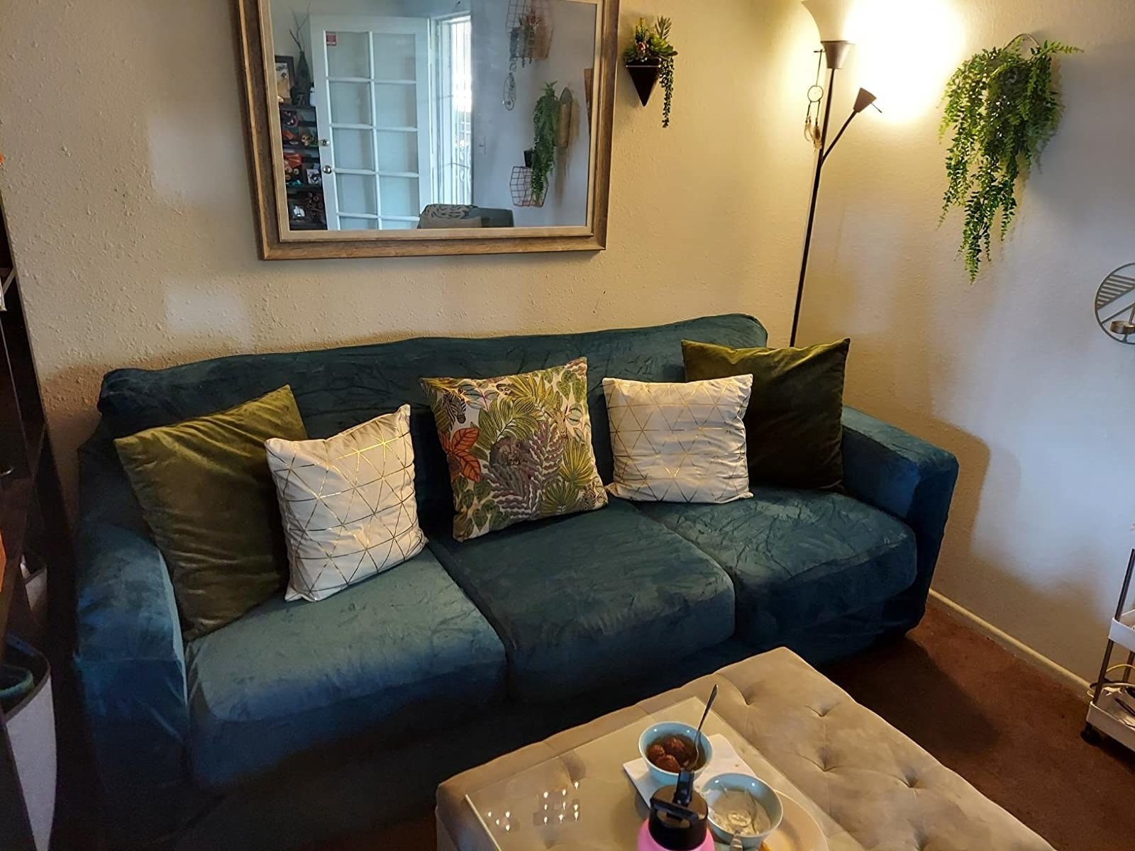 a review photo of the slipcover over a couch in velvet deep green and it fits perfectly