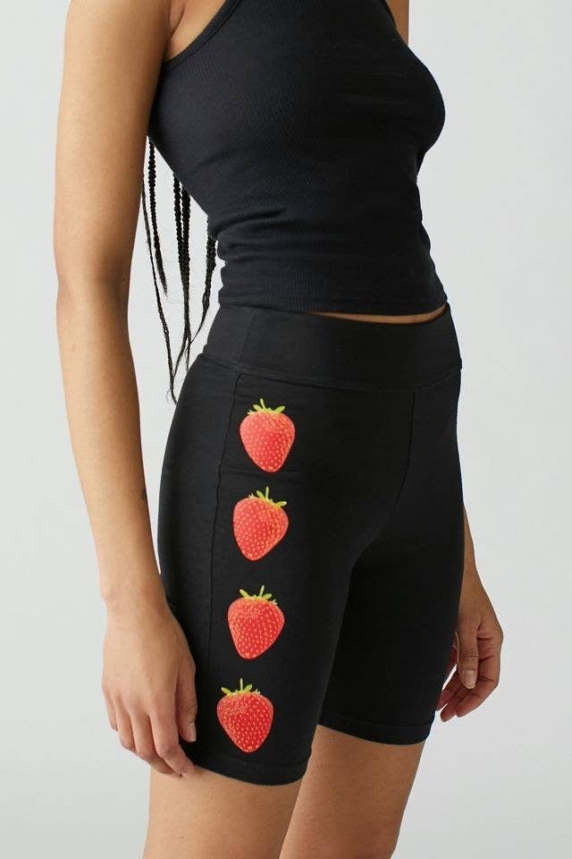 model in black bike shorts with four realistic strawberries printed on the sides