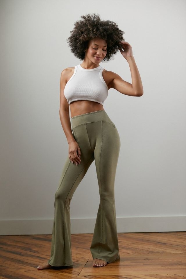 model in olive green flare legging-like pants with seams down the front of the legs