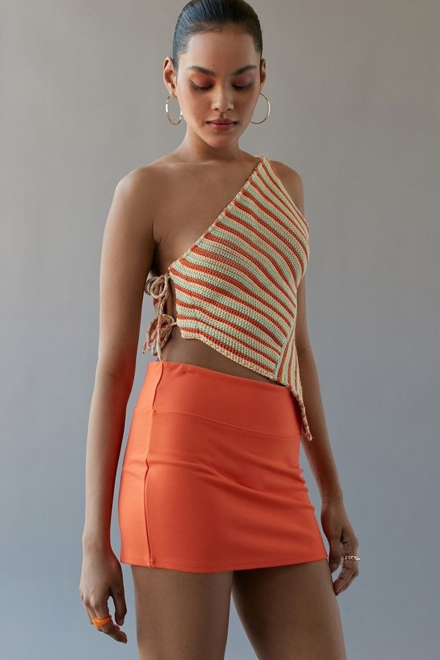 model in an orange low-rise mini skirt