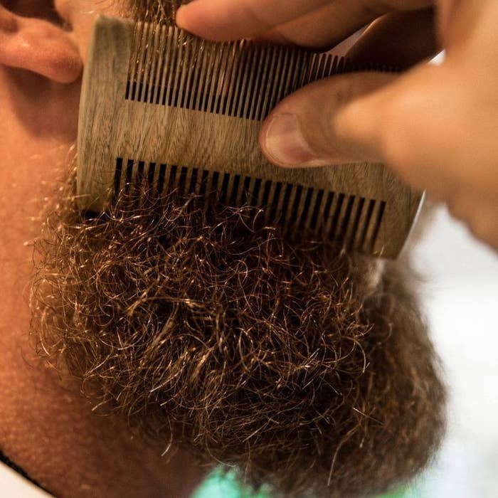 The comb brushing through a mid-length curly beard