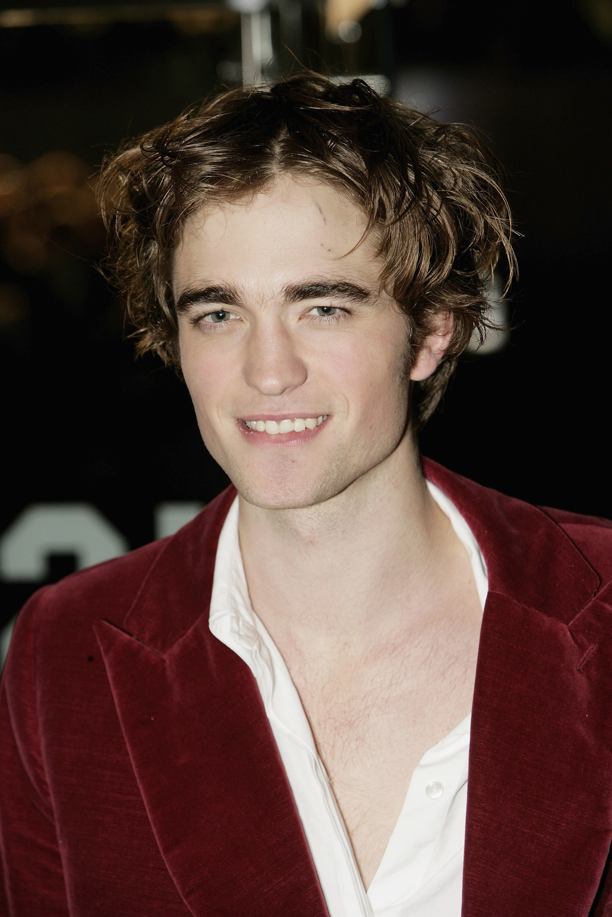 close up of Pattinson in a velvet blazer and messy hair