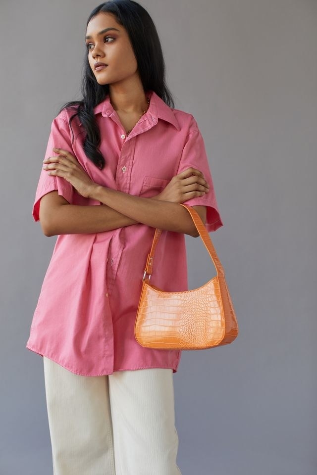 model with an orange alligator skin baguette purse