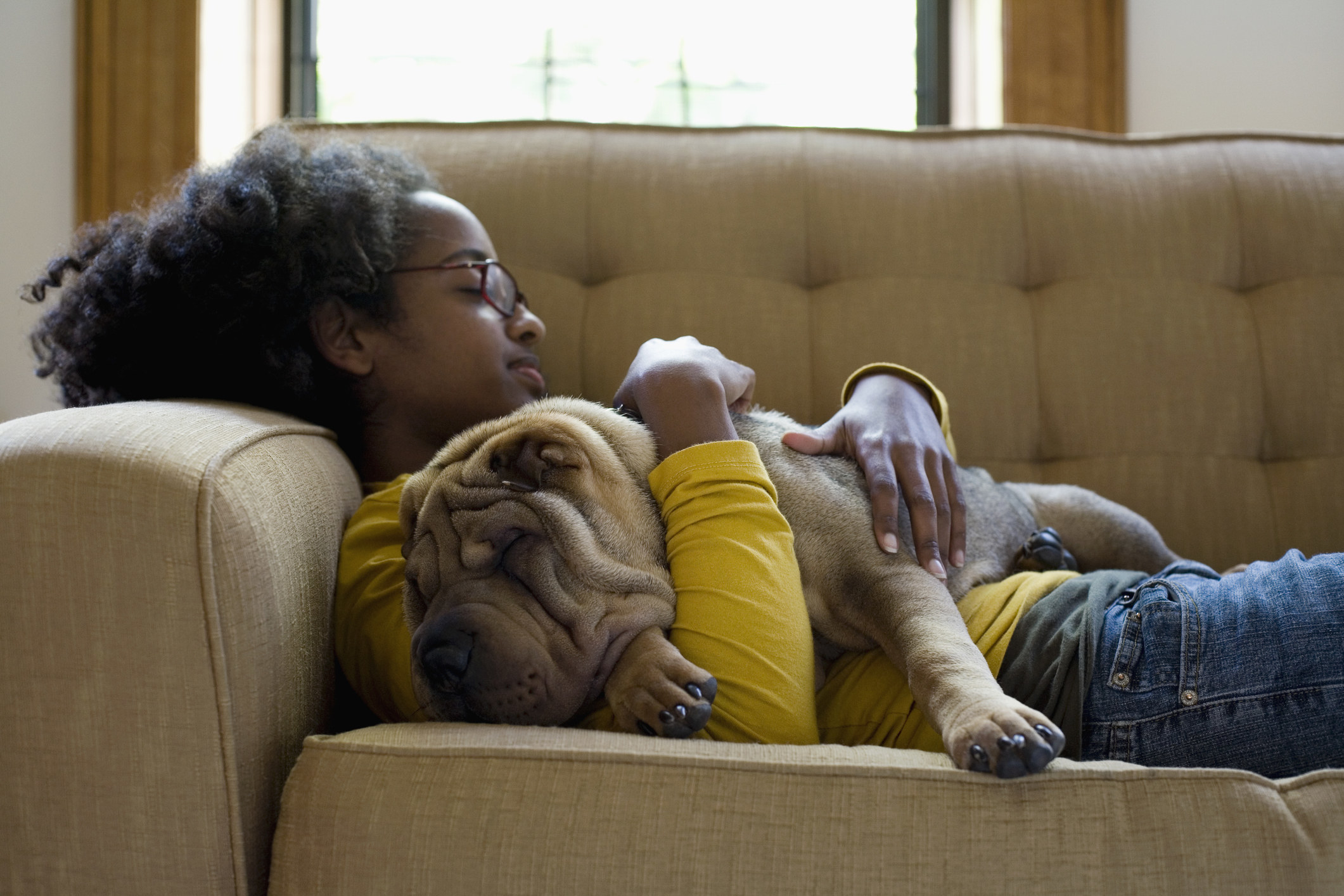A woman naps on a couch with her dog in her arms