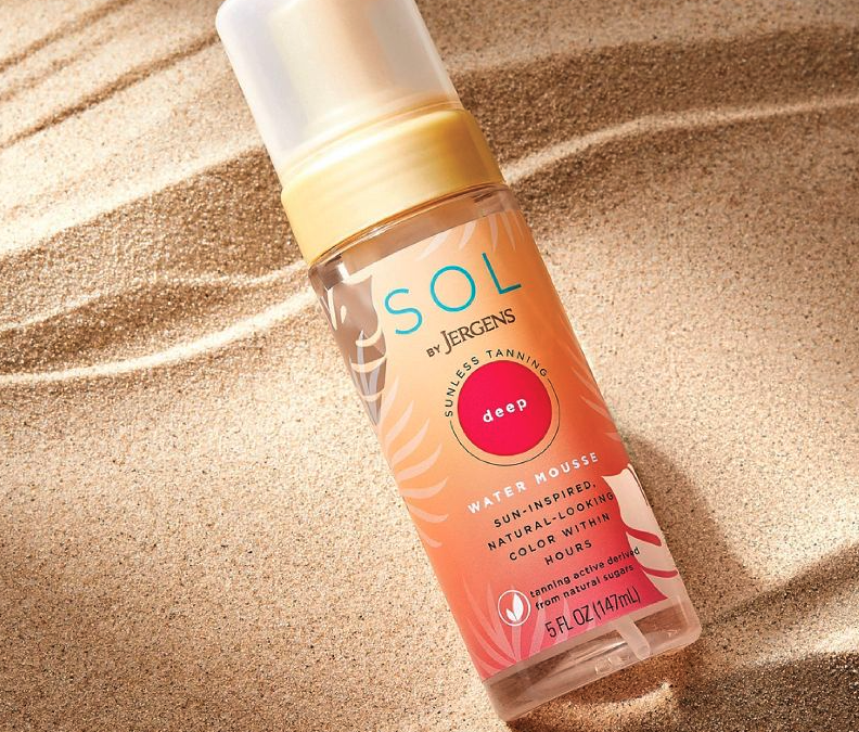 A bottle of the self-tanner set on sand