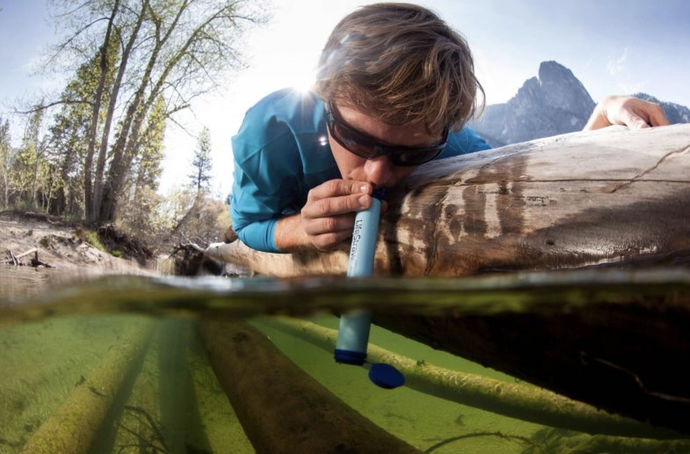 model drinking from a stream through the lifestraw