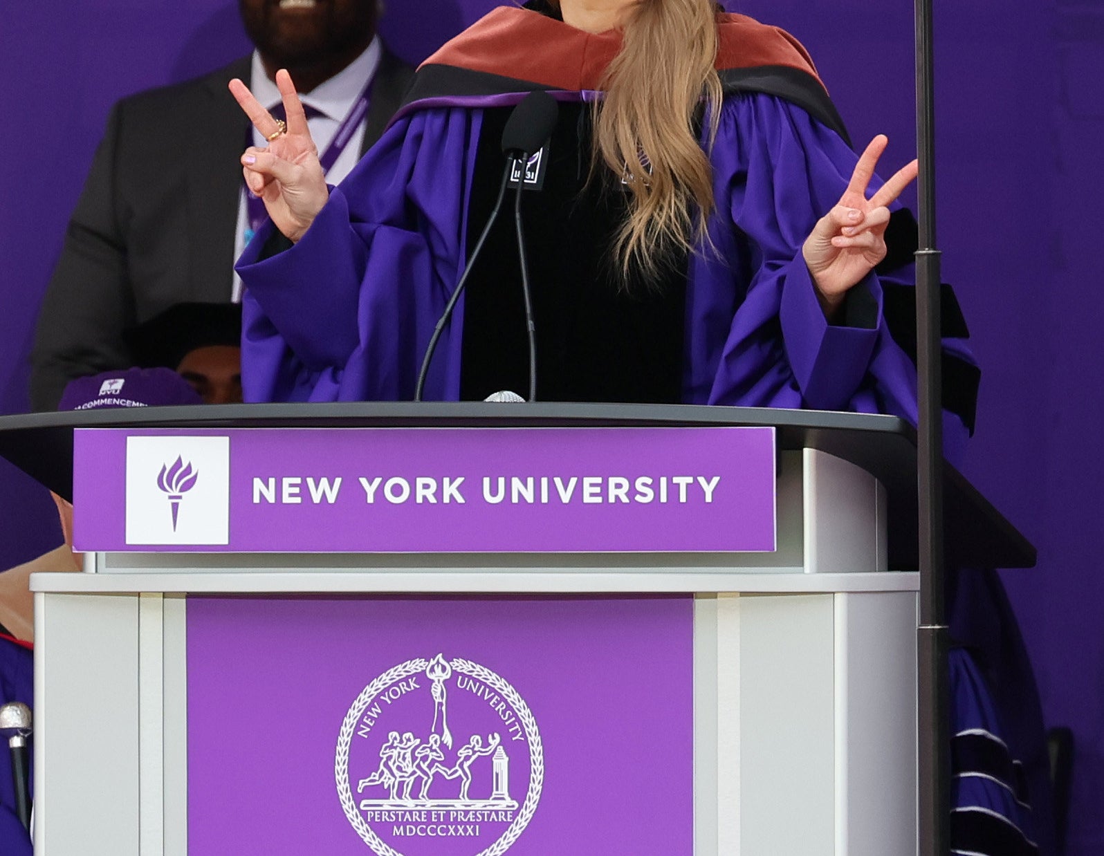 Taylor stands on stage in a cap and gown