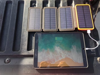 a reviewer photo of someone charging their ipad with the solar charger