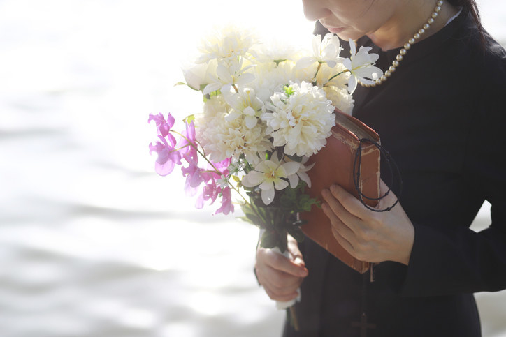 A person wearing black and holding flowers