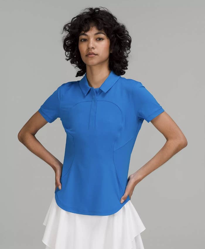 model in the blue short sleeve polo with white skirt