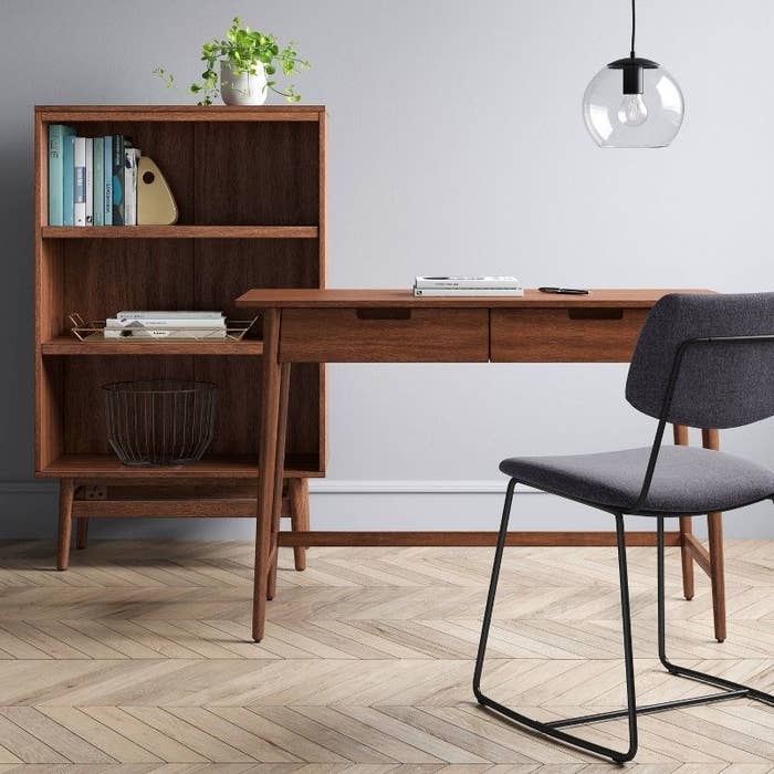 the desk in a home office with a shelf and a chair