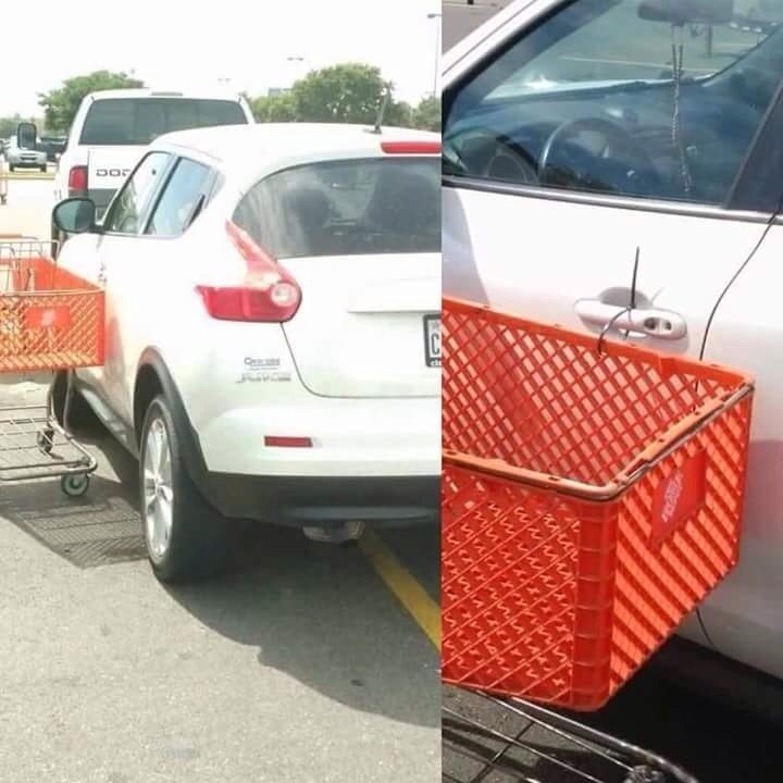A car parked over the line in a parking lot and it has a shopping cart zip-tied to the door handle