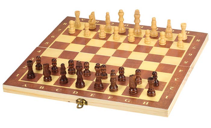 a wood chess board with light and dark wood pieces