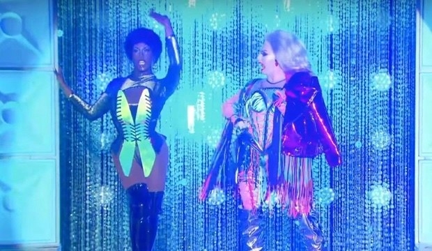 Two drag queens compete on a lit stage