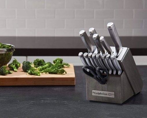 silver calphalon self-sharpening knives and knife block next to vegetables