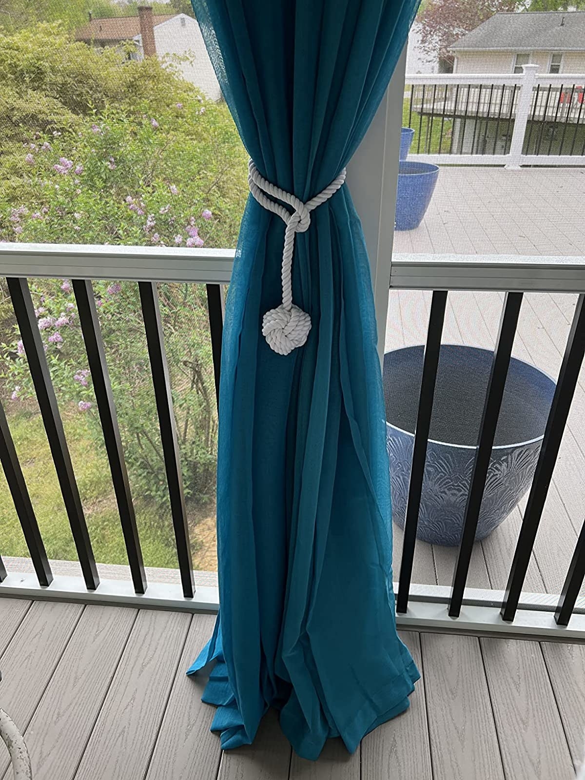 a reviewer photo of the curtain tie back holding a curtain open