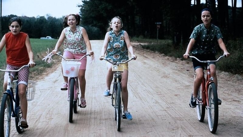 Four girls are seen riding bikes