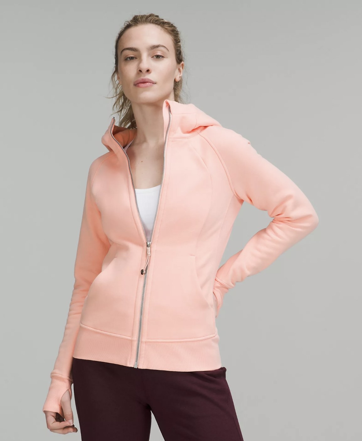 Model wearing the peach full zip sweatshirt over a white tank