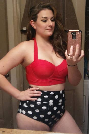 reviewer wearing the bikini with a red top and navy and white polka dot high-waisted bottoms