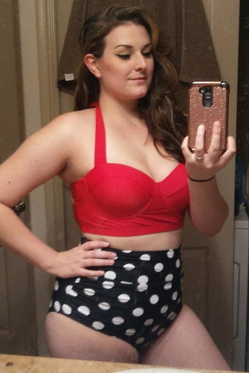 reviewer wearing the bikini with a red top and navy and white polka dot high-waisted bottoms