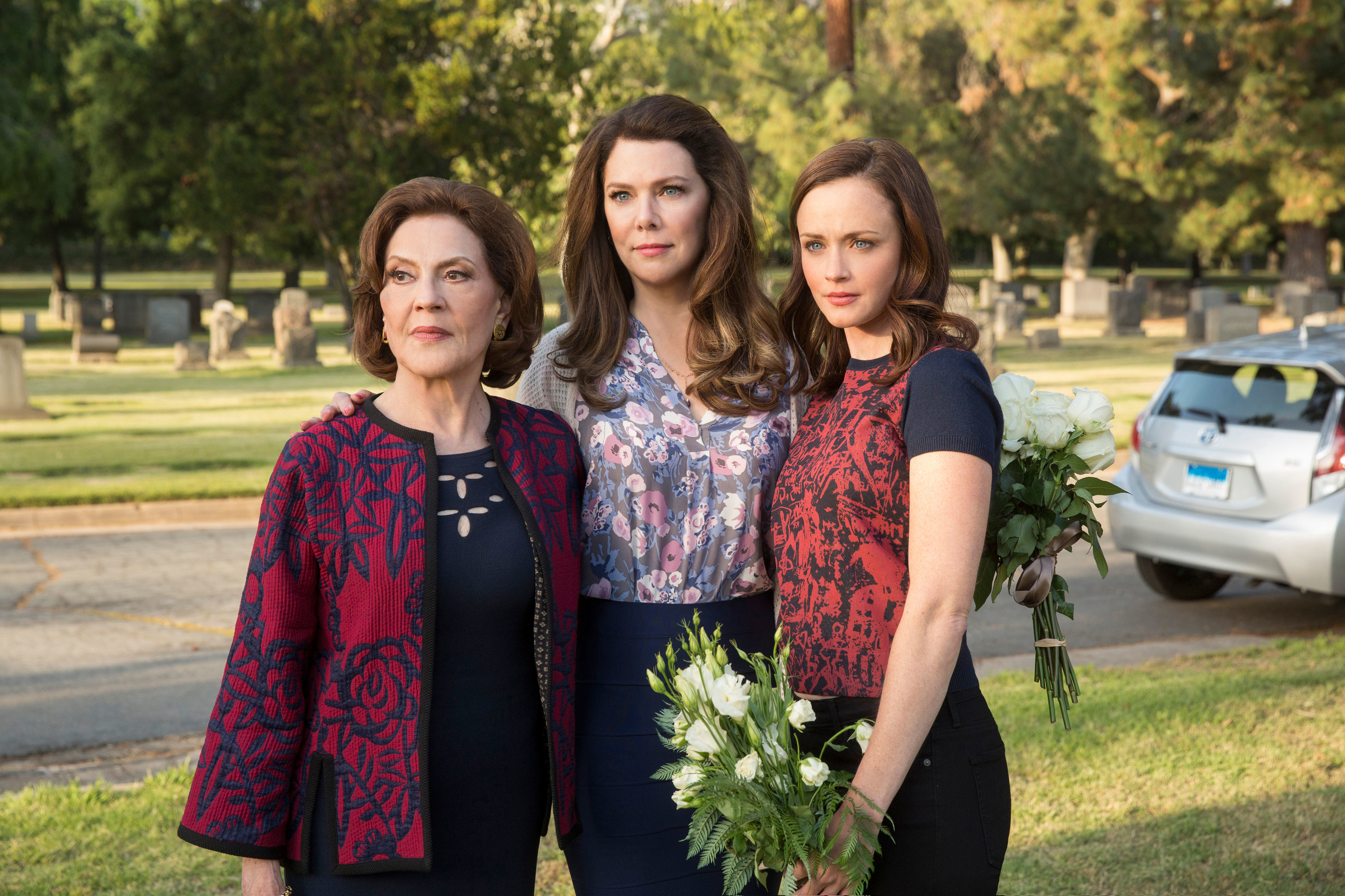 the three main women standing outside holding flowers