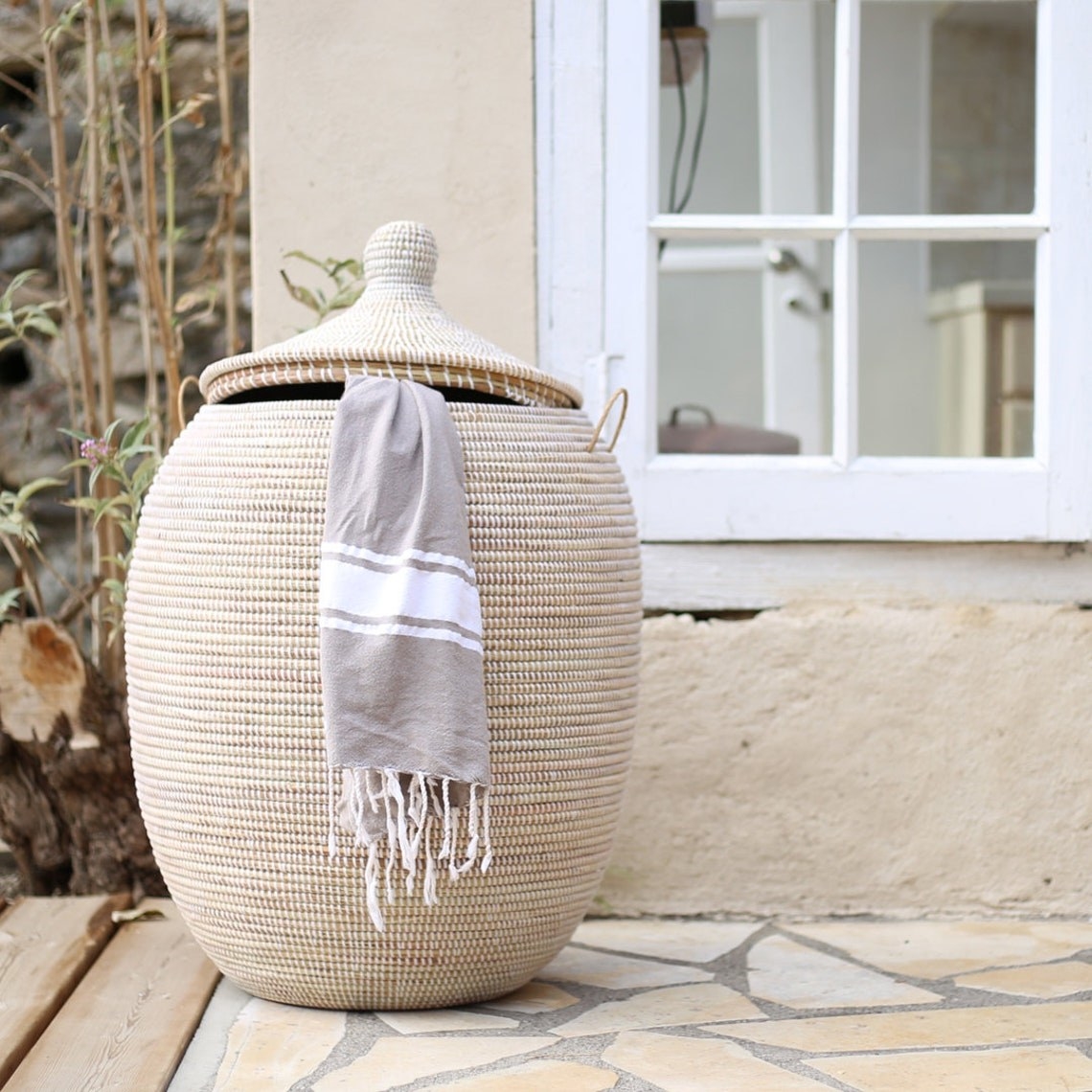 the large, egg-shaped lidded basket with a grey turkish towel peeping out