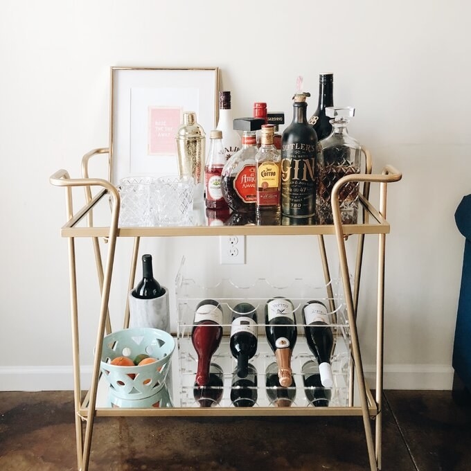 a reviewer photo of the bar cart with bottles and glasses on it