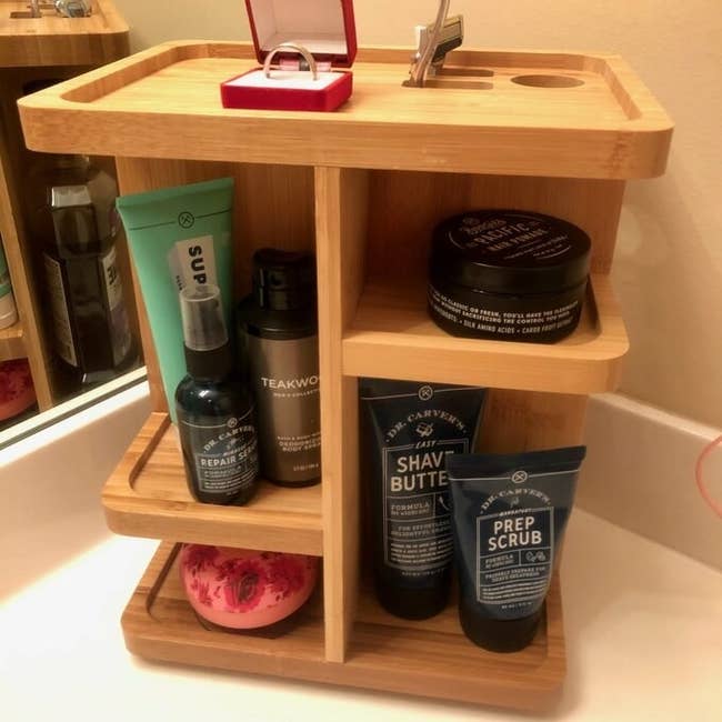 a review photo of the wooden counter organizer with body products on a bathroom counter