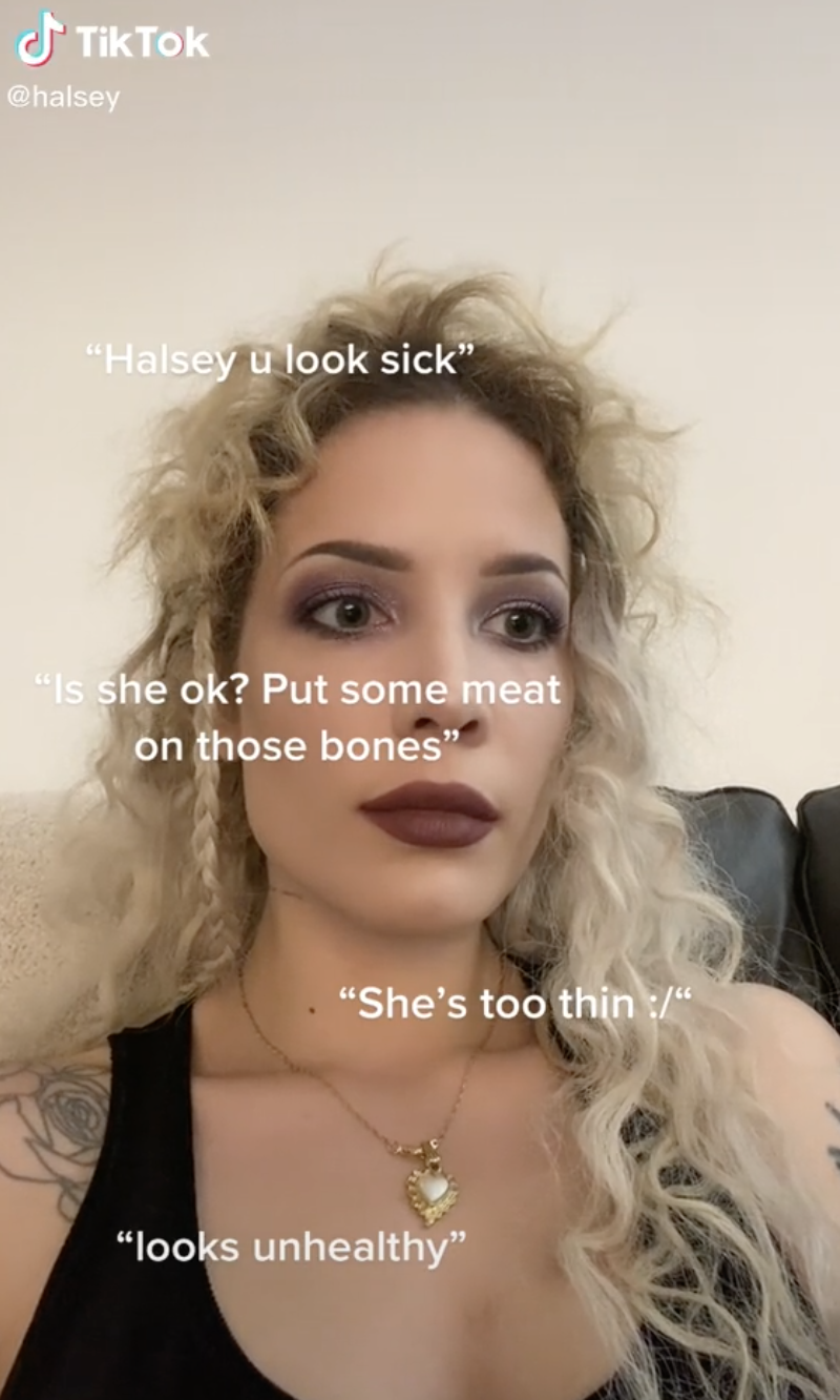 A screenshot of the video in which Halsey stares into the distance as quotes pop up that criticize their body