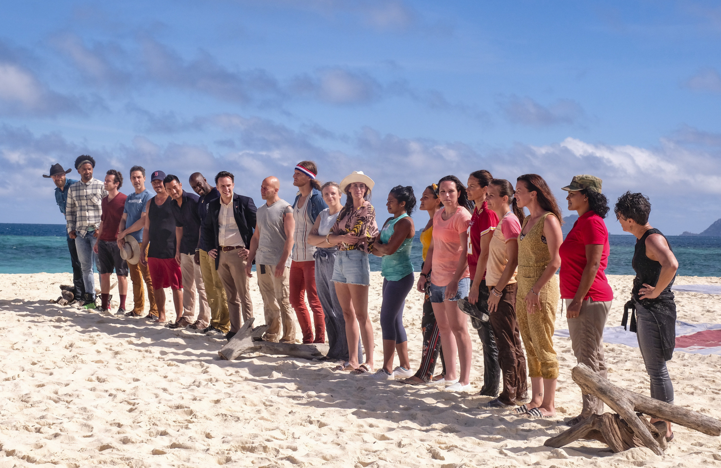 20 former winners stand on a beach together