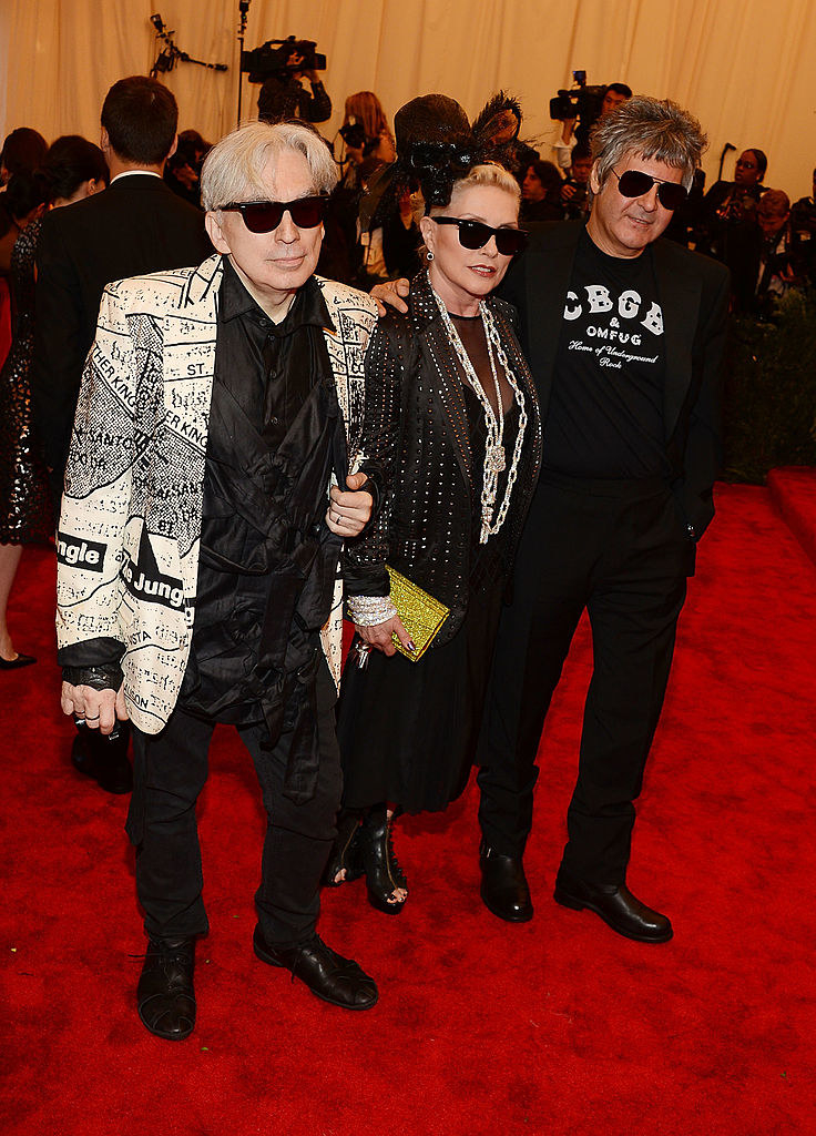 All three wearing black head to toe, with one also wearing a white jacket on top