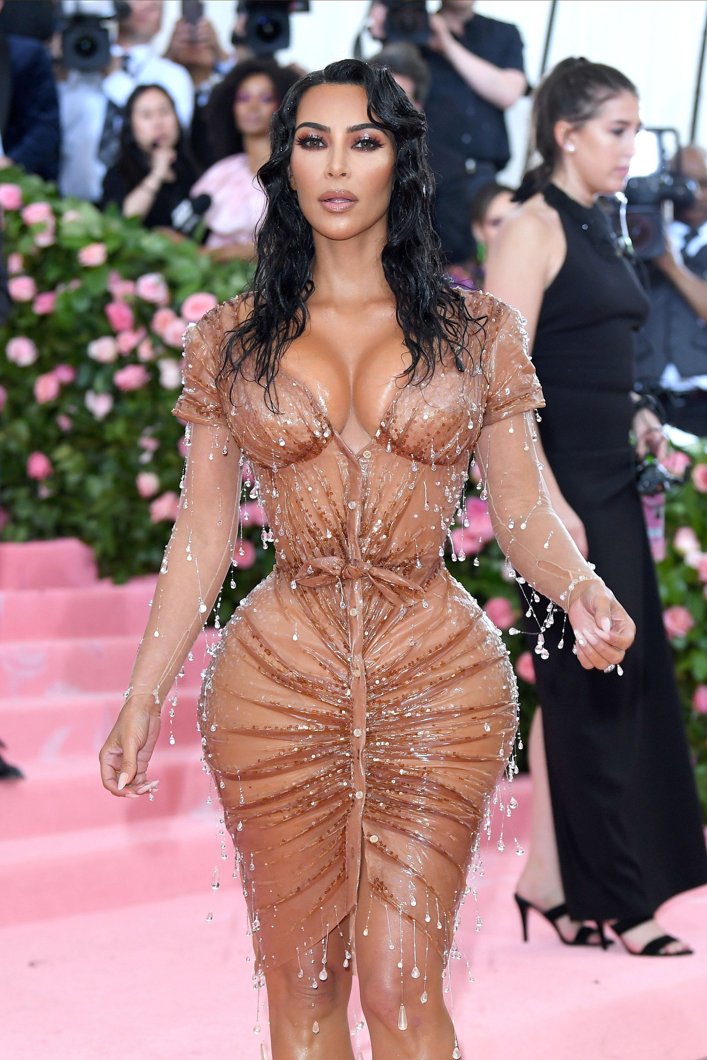 Kim wearing a very tight dress with jewels hanging off it