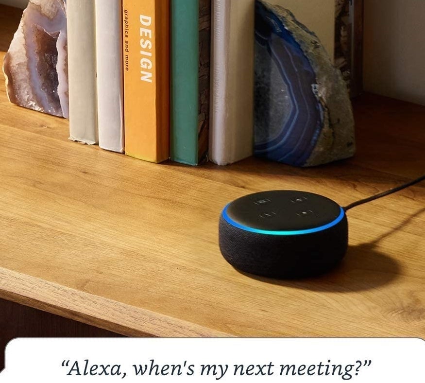 An Alexa speaker on a shelf next to some books
