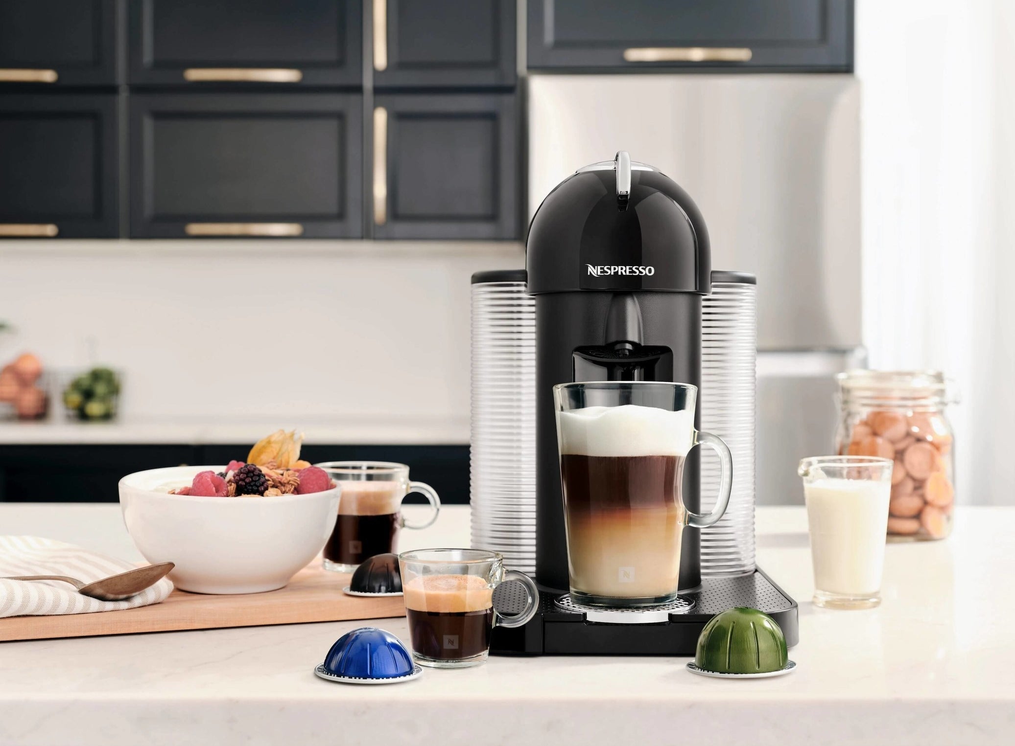 A Nespresso machine on a counter surrounded by cups of coffee