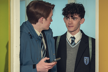 Nick and Charlie look at each other as they walk through a door wearing school uniforms