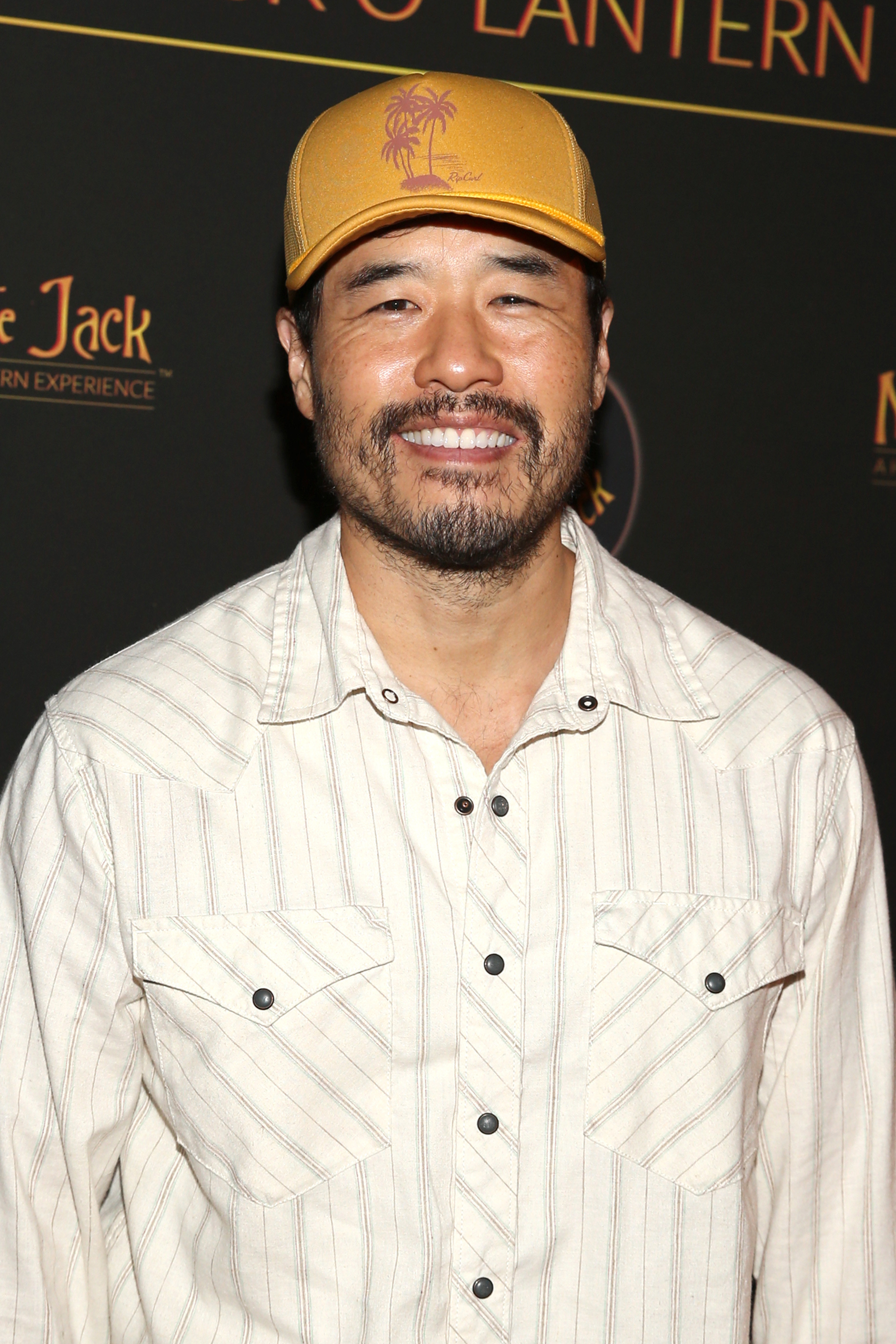 Randall smiling with a yellow baseball cap and white striped shirt