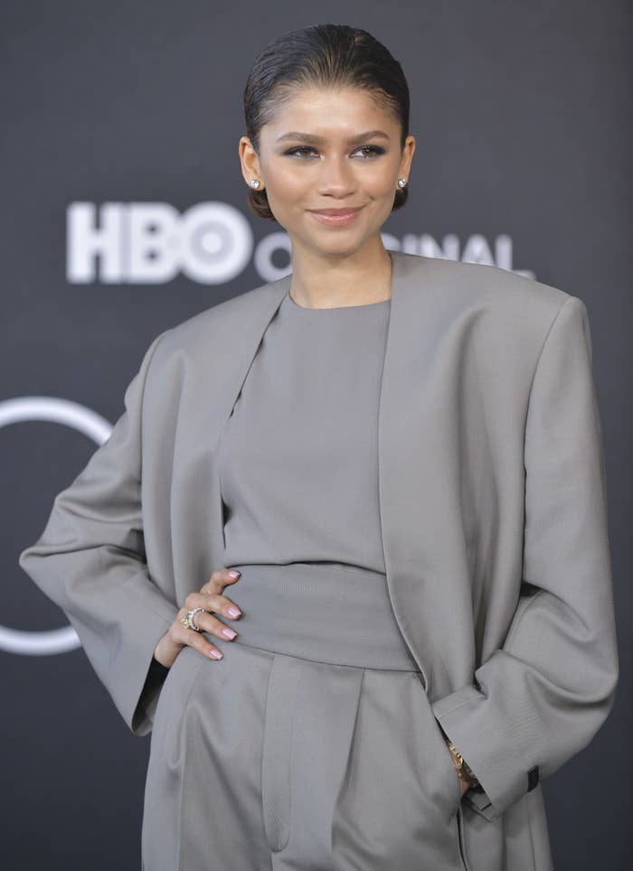 Zendaya wearing a suit while posing with her hand on her hip